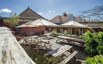 The Garden Bar on a sunny day with wooden tables and parasols. Brighton Beer Garden