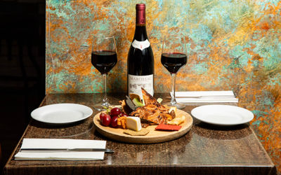 table laid out for two people with bottle of wine, two glasses of red wine and charcuterie board at Petit Pois
