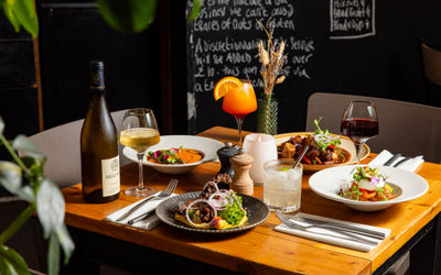 side shot of the corner table at Mange Tout laid out with lunchdishes and bottle of wine and cocktails