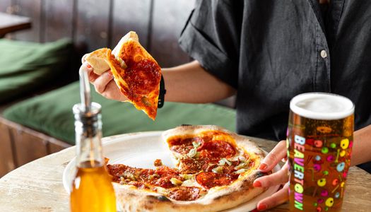 hand holding piece of pizza