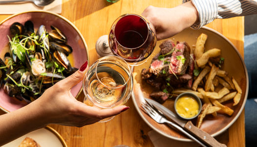two people having a toast with glasses of wine at Mange Tout
