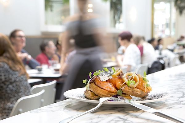 Smoked salmon brunch plate sat on the bar with a busy restaurant in the background