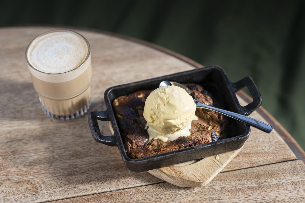 Baked cookie dough in a skillet with Gelato Gusto gelato and a latte served in a glass. 