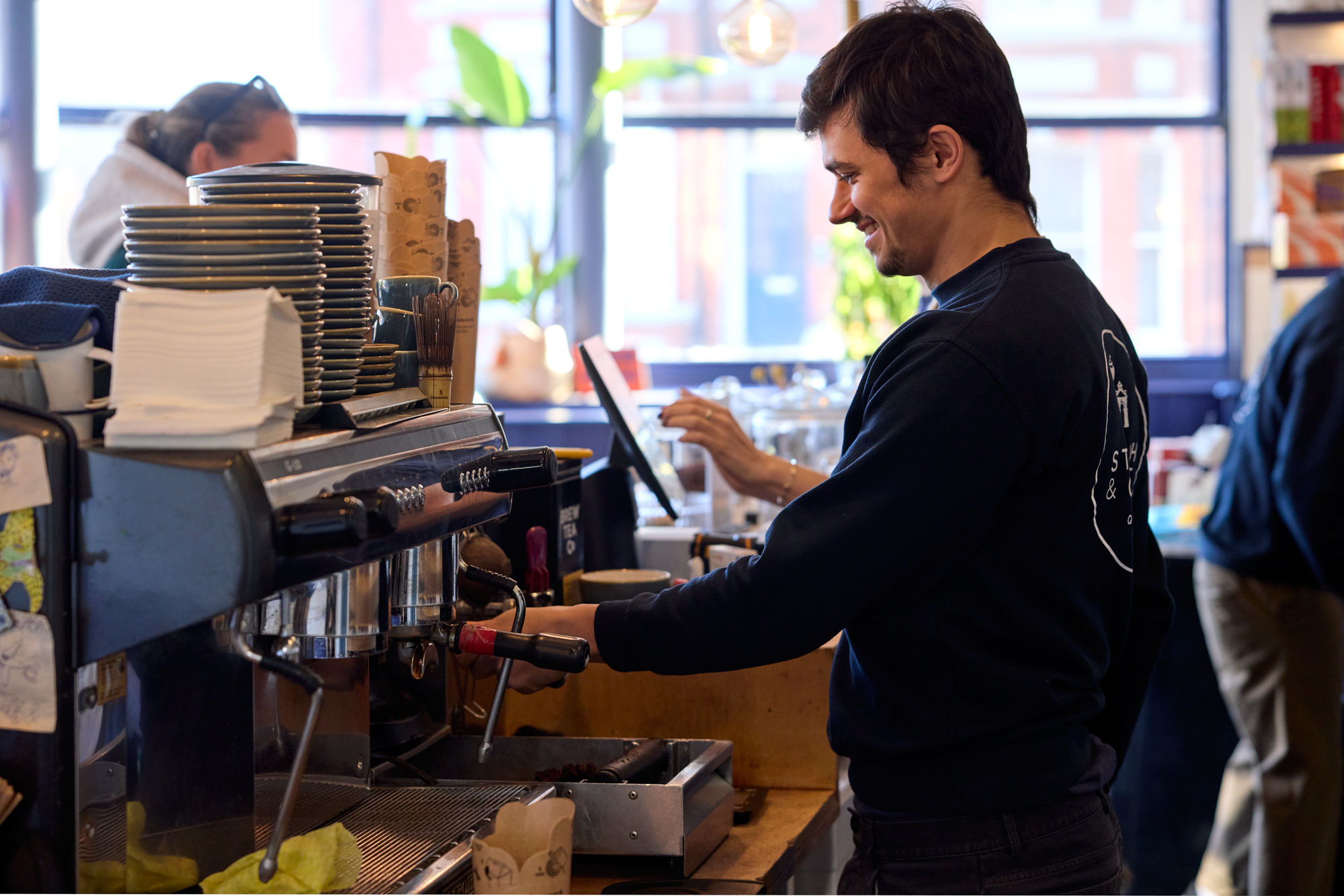a man smiling and preparing a coffee