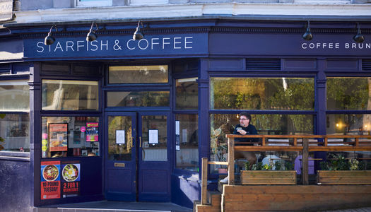 Starfish and Coffee - exterior shot of the venue with Tony sitting and having a coffee in front of it. Voted best cafe in Brighton in 2026 at the BRAVO Awards