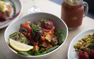 A vegan breakfast bowl with avocado and roasted vegetables. Served with a bloody Mary with a stick of celery.