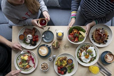 Overhead table shot with people sitting at the table eating a variety of brunch dishes.