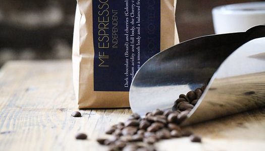 Specialist Coffee Roasters and Brighton Coffee Shop. Cafés & Coffee Shops with Wi-Fi, fresh coffee beans ready to grind at Trading Post Coffee. Blue labelling in paper bag. Beans already roasted laid on the table.
