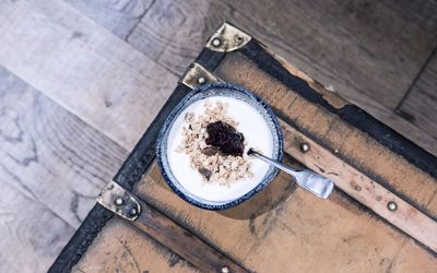 breakfast at the Coppa Club in Brighton. The yoghurt is in a speckled clay blue bowl and on a rustic looking table. This venue is part of the breakfast Brighton guide