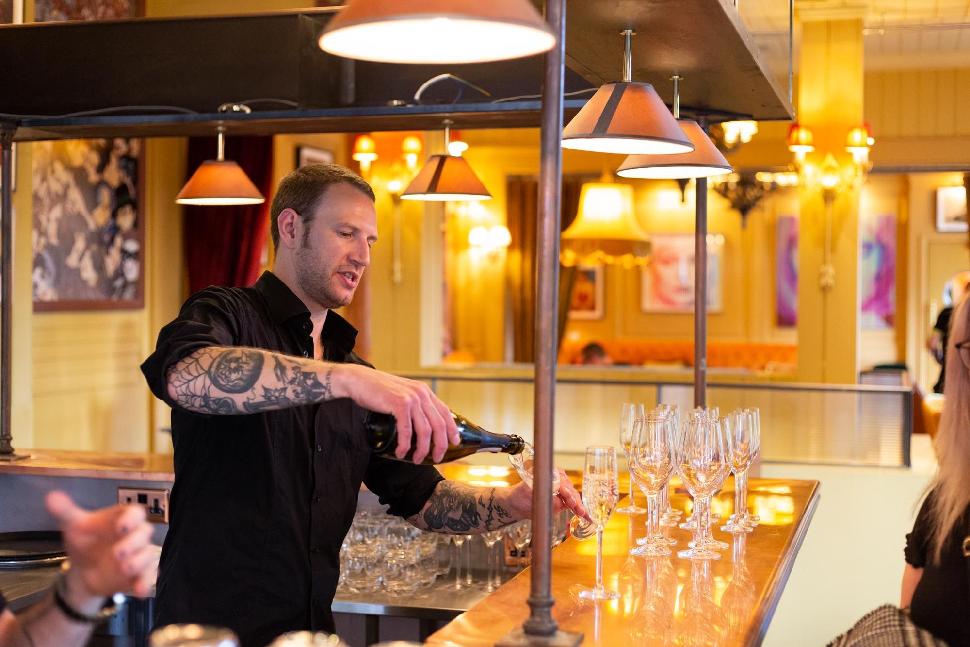 bartender sipping prosecco into glasses