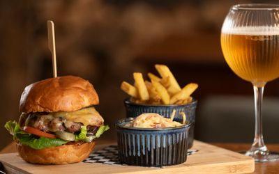 delicious looking burger served with coleslaw, chips and glass of beer at the new inn