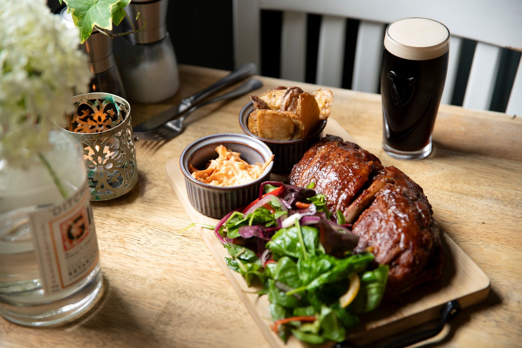 meat, potatoes, salad, sauce and dark beer served on the wooden table at the new inn