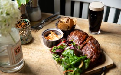 meat, potatoes, salad, sauce and dark beer served on the wooden table at the new inn
