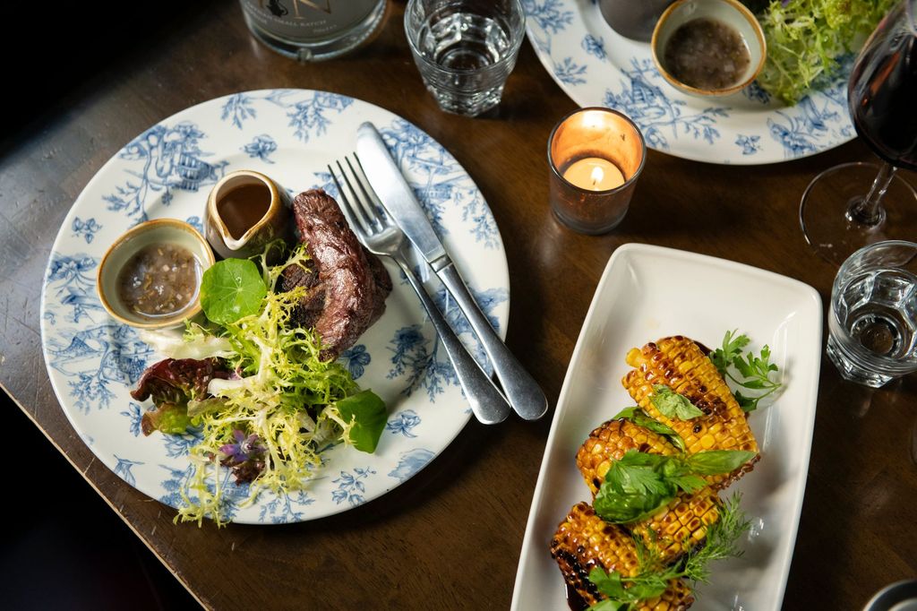 table laid out with main dishes including plate with corns and plate with vegetables and sausage