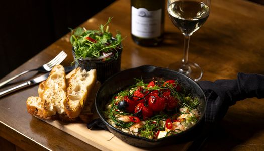 over head shot of the lunch dish at the new inn, bread, salad and tomato dish in the black pan served with glass of red
