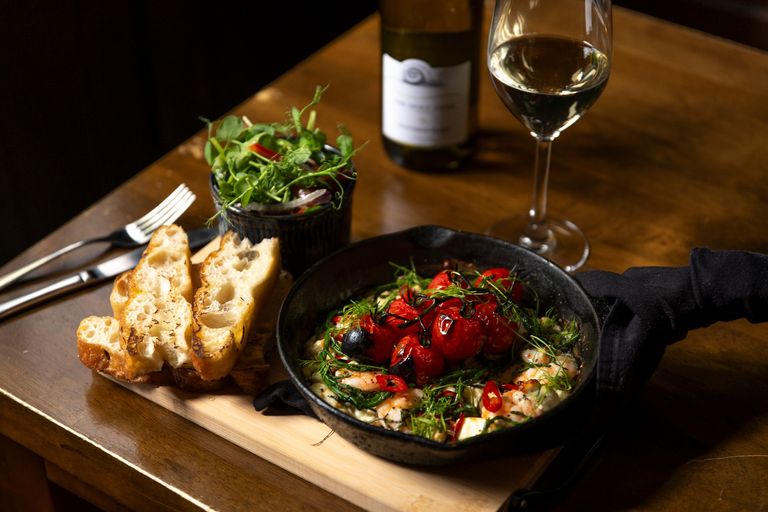 over head shot of the lunch dish at the new inn, bread, salad and tomato dish in the black pan served with glass of red