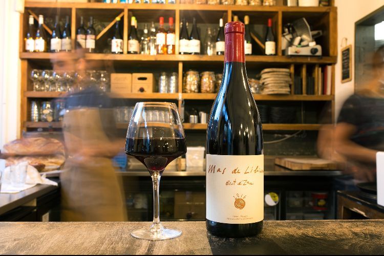 A glass and bottle of red wine on the bar inside the restaurant.