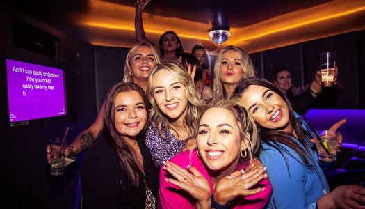 A group of 6 ladies enjoying karaoke at Lucky voice Brighton. A karaoke screen in the background. One of Brighton's favourite karaoke bars. Karaoke Brighton