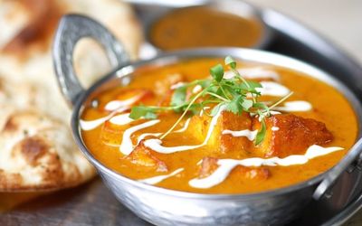 Kadai Paneer Curry in Curry Leaf Cafe Brighton, served in a metal dish with breads and dip.