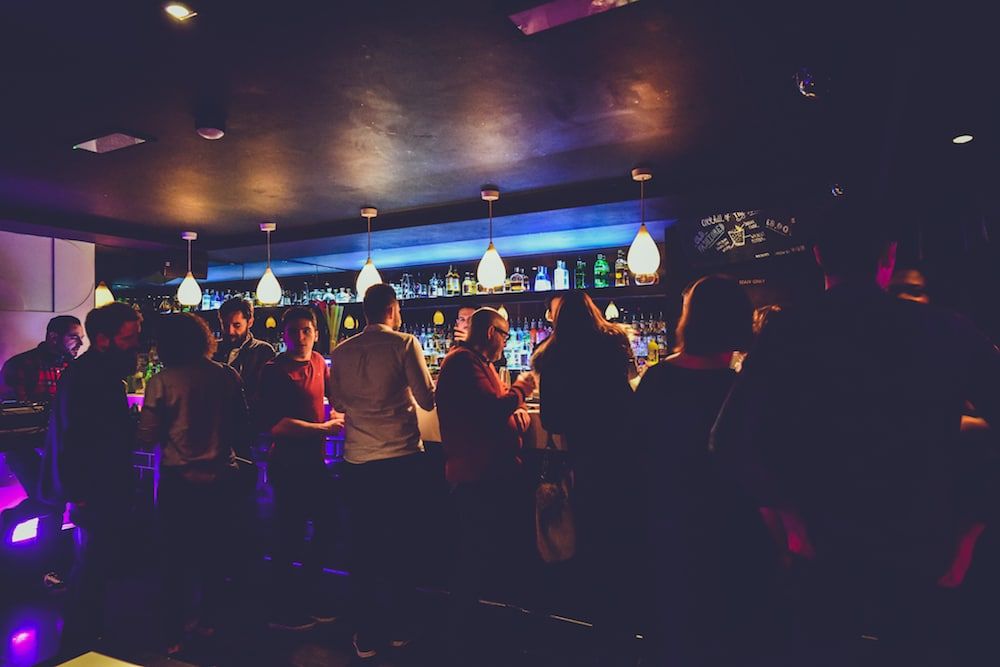 a dimly lit cocktail bar with customers enjoying their drink