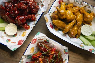 Trays of chicken wings cooked in different sticky sauces with a side of celery and creamy dip