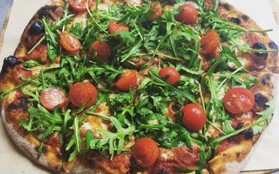 Homemade pizza with fresh cherry tomatoes and rocket.