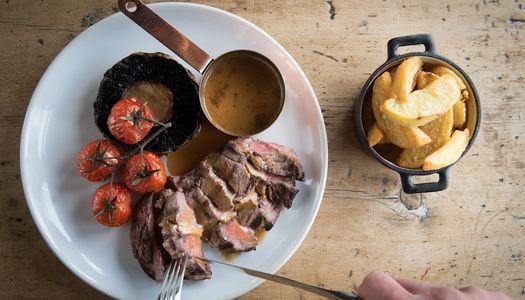 Steak and chips with a sauce and grilled tomatoes.