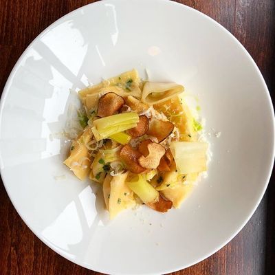 A large porcelain bowl of homemade pasta with Parmigiano-Reggiano and leeks