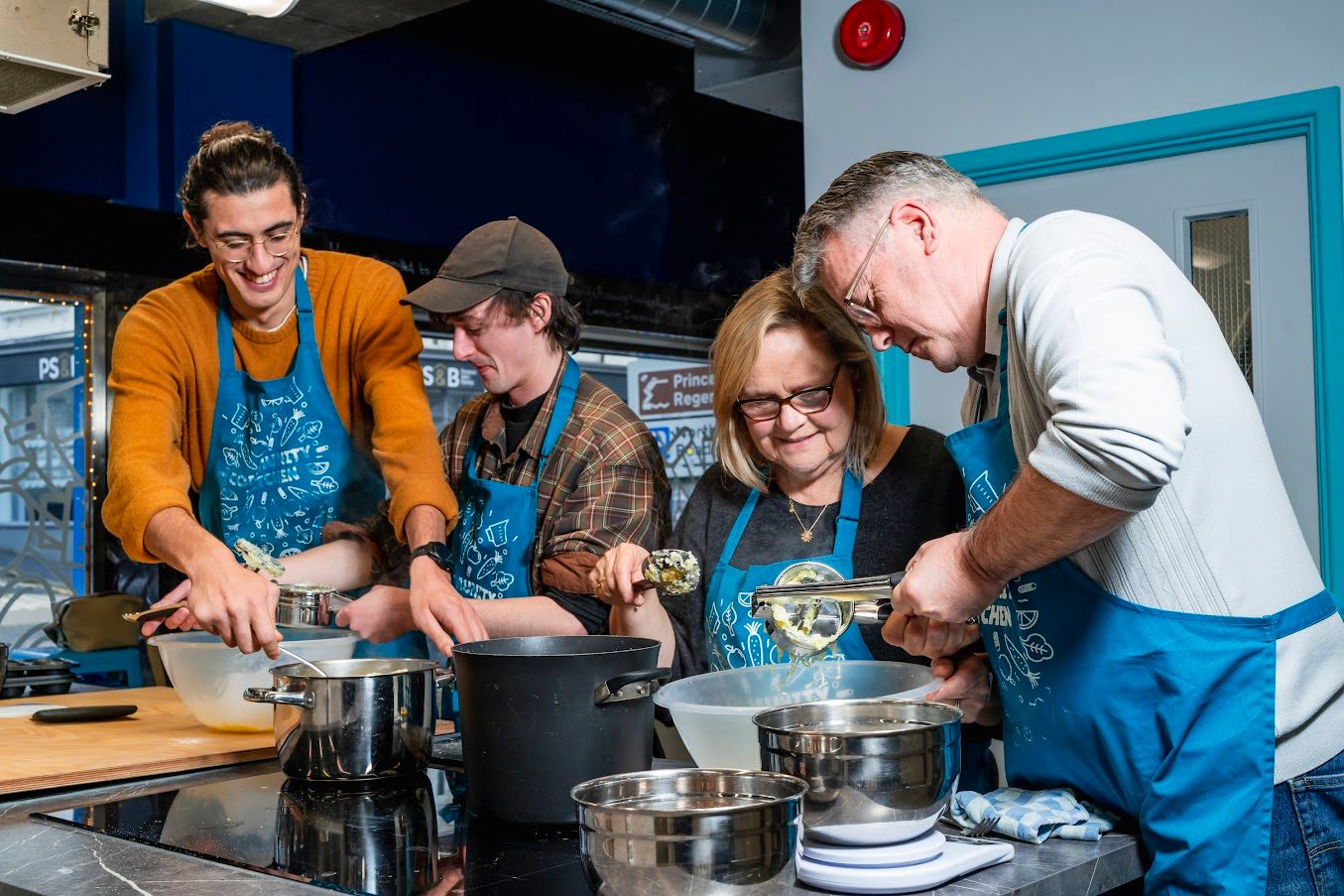 Brighton Community Kitchen - four people cooking dishes at the cooking class