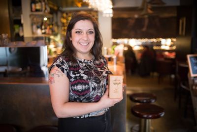 A person holding an award inside the Plotting Parlour next to the bar