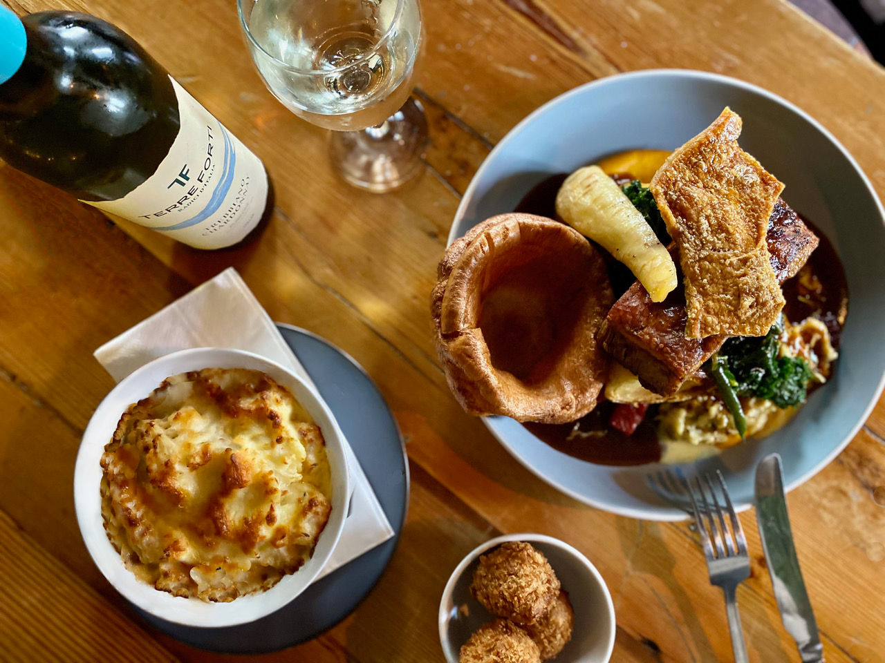 over head shot of the Sunday Roast with bottle of wine served on brown wooden table at The Mesmerist brighton