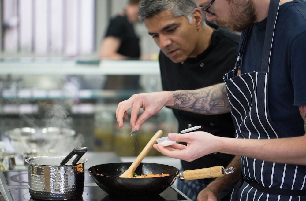 Men cooking curry over a wok