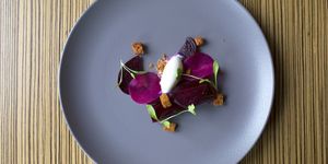 Beetroot Dish garnished with microgreens served on a purple ceramic plate.
