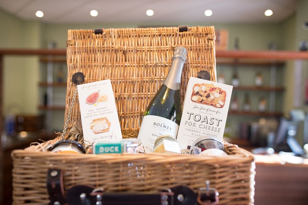A wicker hamper basket filled with a selection of food items and wine