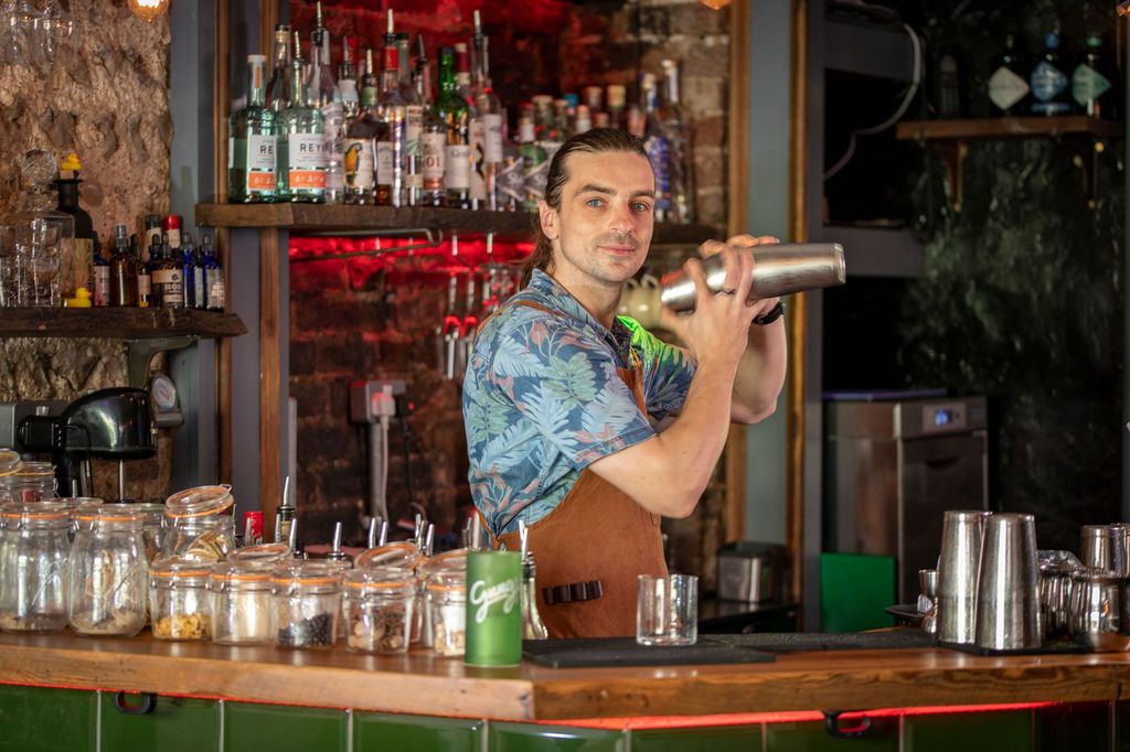 bartender preparing alcohol free Brighton cocktails. The bartender is at Gung Ho. The bar is wooden with a back drop of drinks glasses behind.