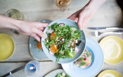 A blue bowl of salad with radishes and squash