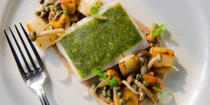 A piece of white fish with a herb crust served with capers and wild mushrooms.
