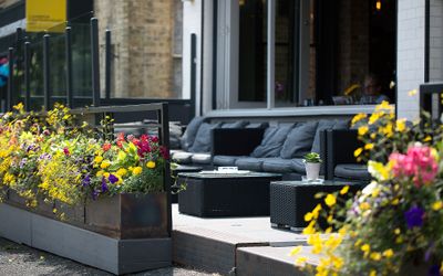 Alfresco seating at Libation with cushioned black sofas and summer flowers