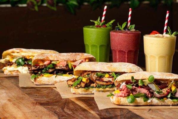 four delicious looking social board sandwiches served with colourful smoothies