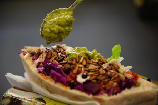 Homemade pitta stuffed with colourful salads topped with toasted seeds and a spoon of fresh guacamole