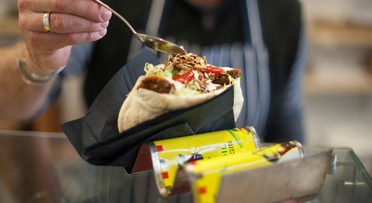 Falafel being assembled at Smorls. Toasted seeds being sprinkled on a full pitta