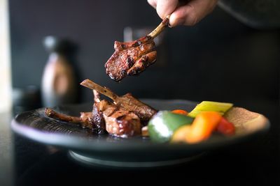 Chargrilled skewered meat with mixed Mediterranean vegetables served on a black dish.