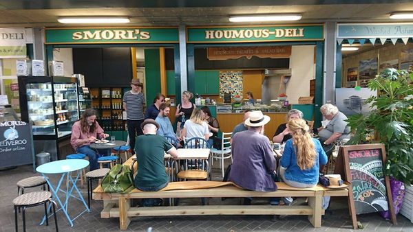 People sitting outside on wooden benches at Smorls which is located at Brighton Open Market