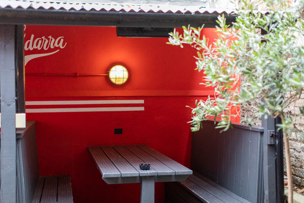 A beer garden booth at Haus on the Hill, with a red wall behind it and a tree in front