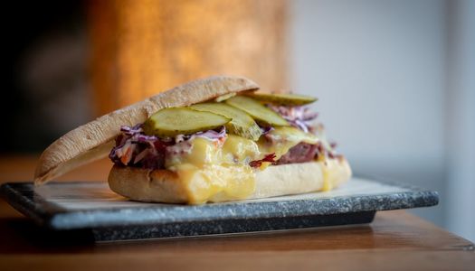 Panini sandwich with melted cheese, red cabbage and pickles. Served on a marble tray.
