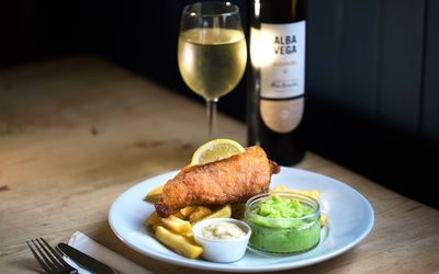 Battered fish with chunky chips and pots of mushy peas and tartare sauce. Served with a bottle of white wine.