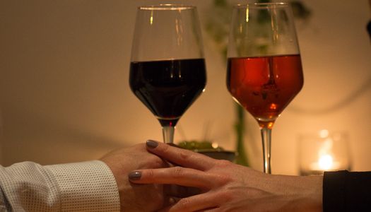 Valentine's Day Brighton in Brighton. Pictured, a romantic couple holding hands with a rose and red wine in hand. Candlelit setting and low light.