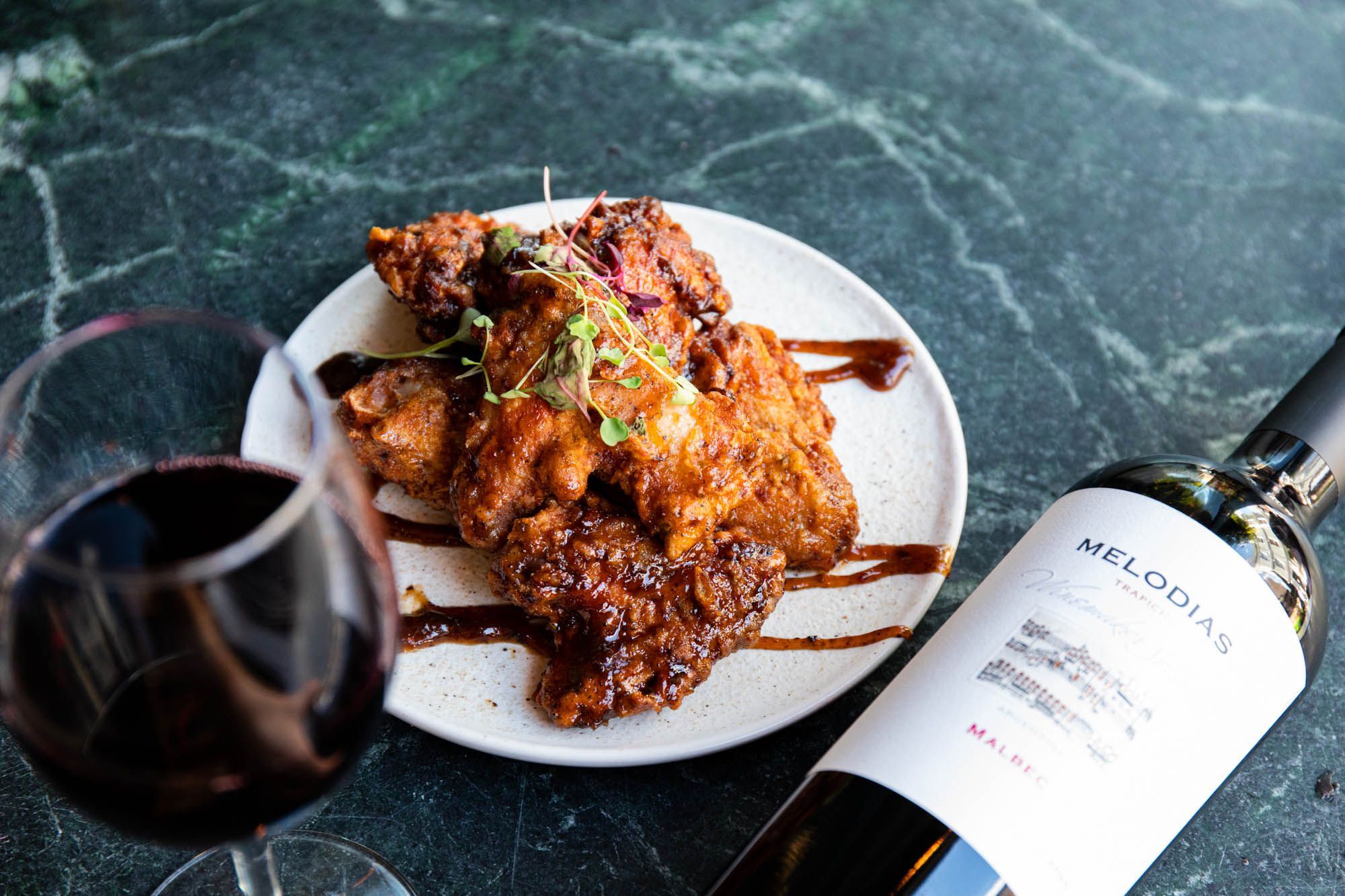 over head shot of the meat dish served with glass of wine on the dark blue marble table