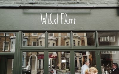 Outside of Wild Flor during the daytime. Photography of the front entrance and windows with green paintwork.