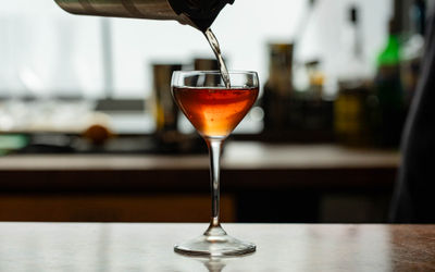 An amber coloured drink being poured with the natural light shining through the back.